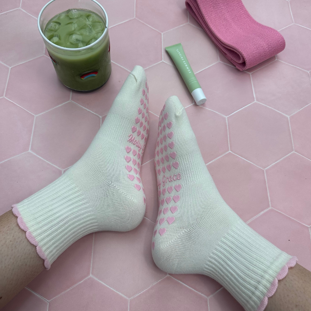 Cream sock with a pink ruffle and pink heart grips