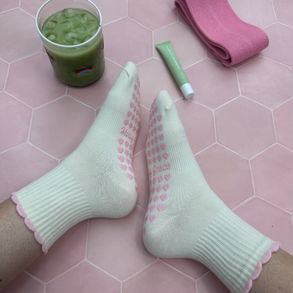 Cream sock with a pink ruffle and pink heart grips